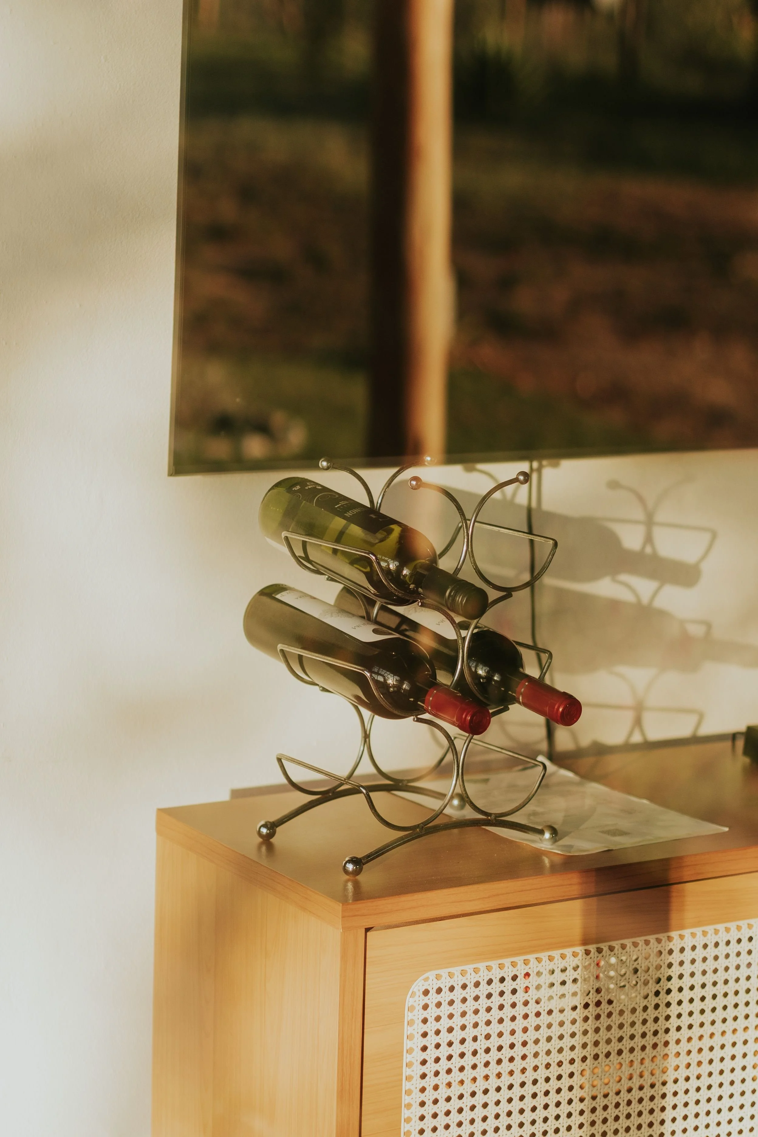 Bottles sit horizontally on a decorative frame on a dresser