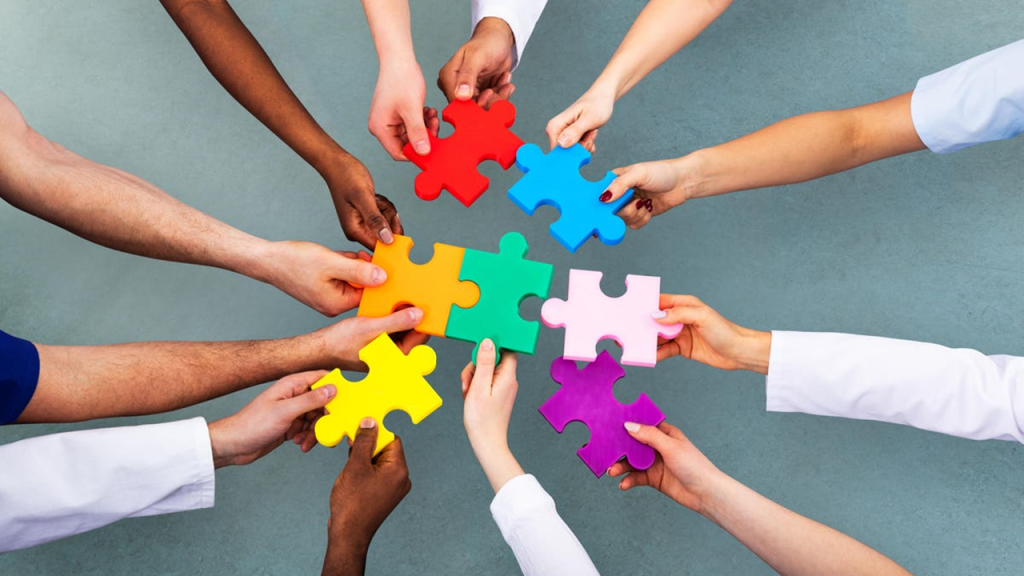 Hands holding puzzle pieces, reaching to the center to put them together