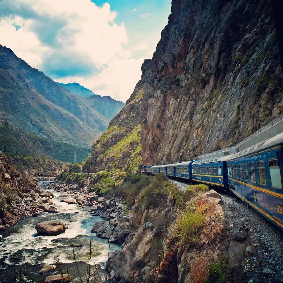 A train traveling through a narrow mountain canyon with a river running below.