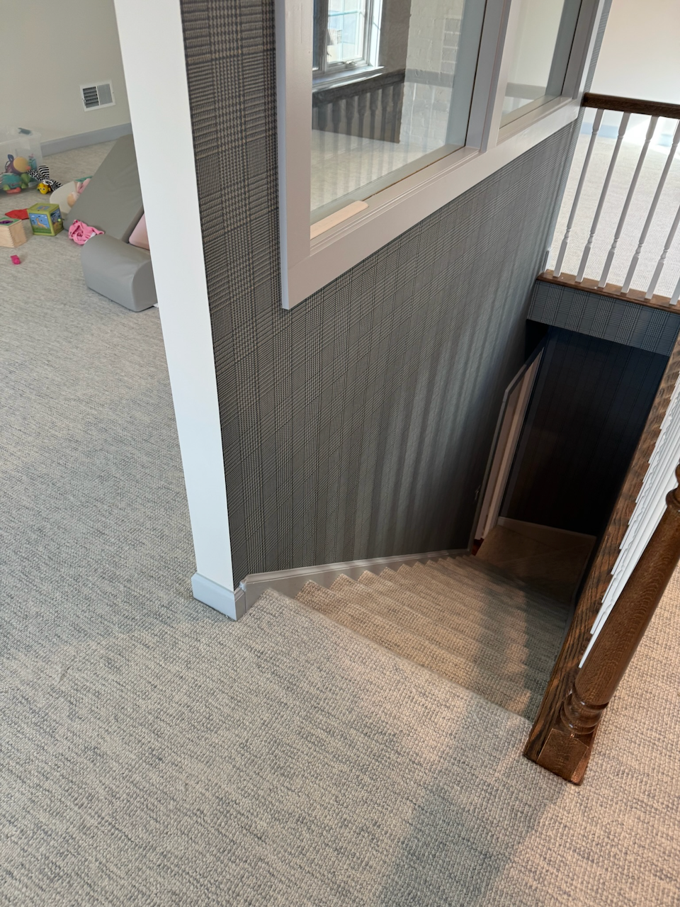 Stairwell wall with plaid trim treatment and oak newel posts.