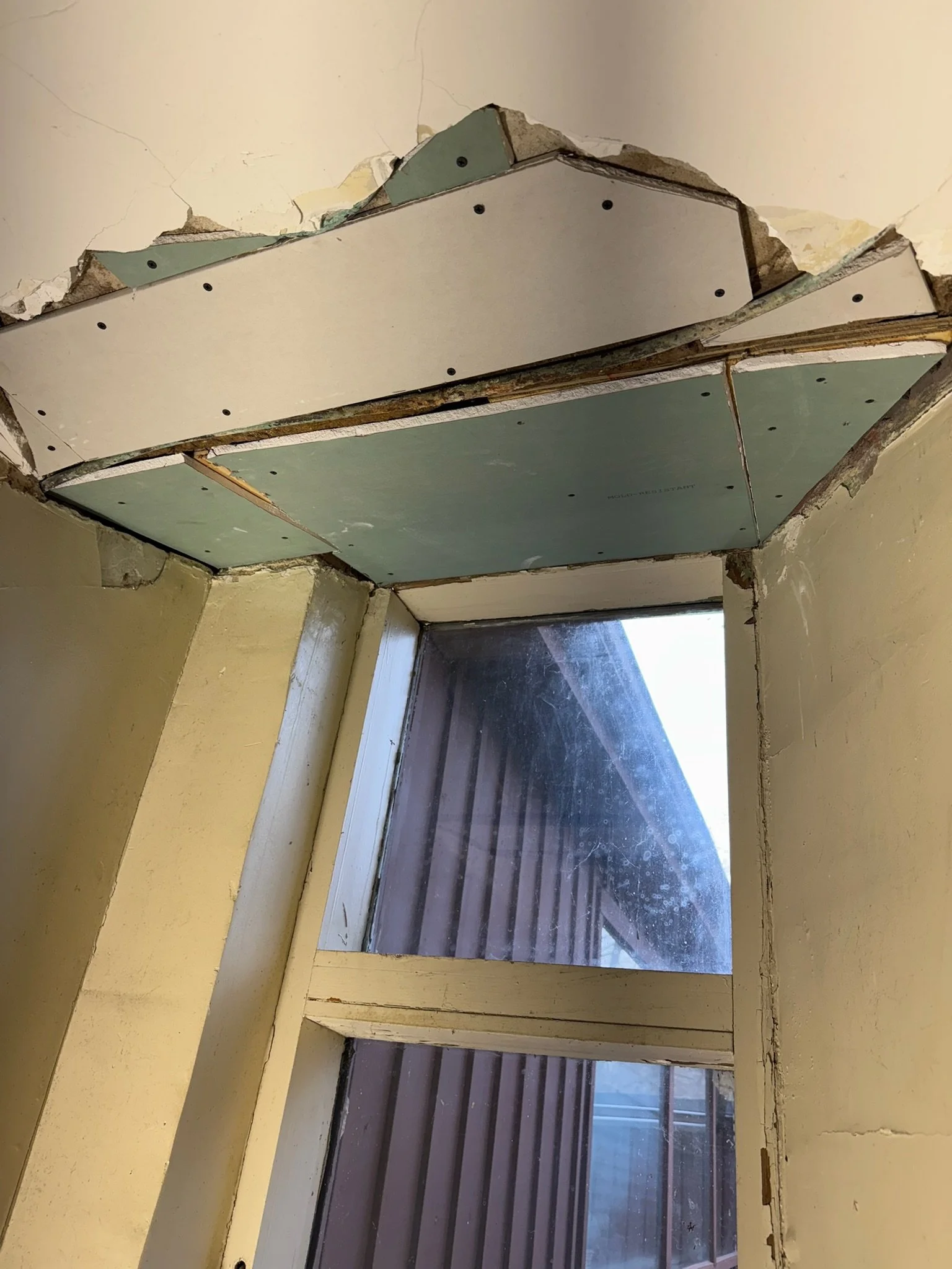 Ceiling repair in progress: drywall patches fitted above the window.