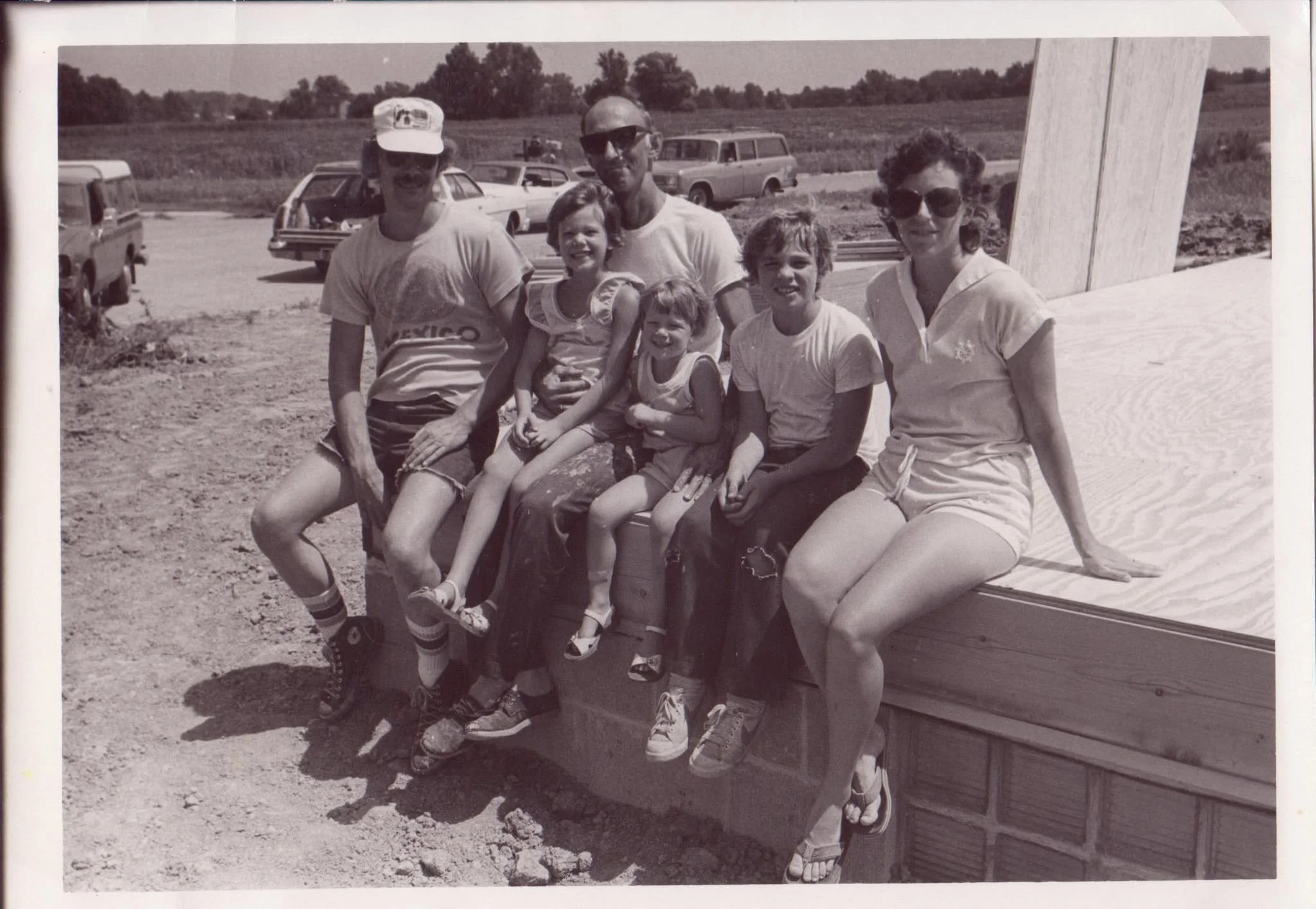 Young Sarah sitting on her grandfather’s lap with her family at the house he was building