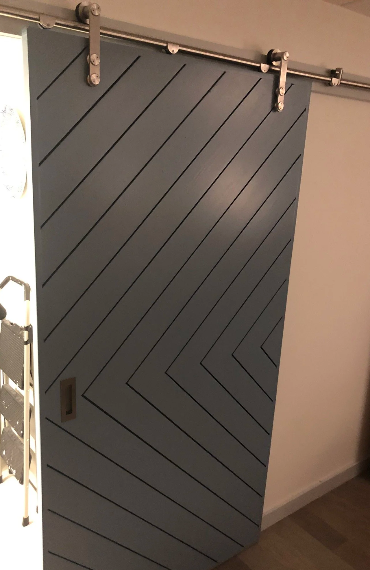Custom sliding barn door with chevron wood panels and black hardware