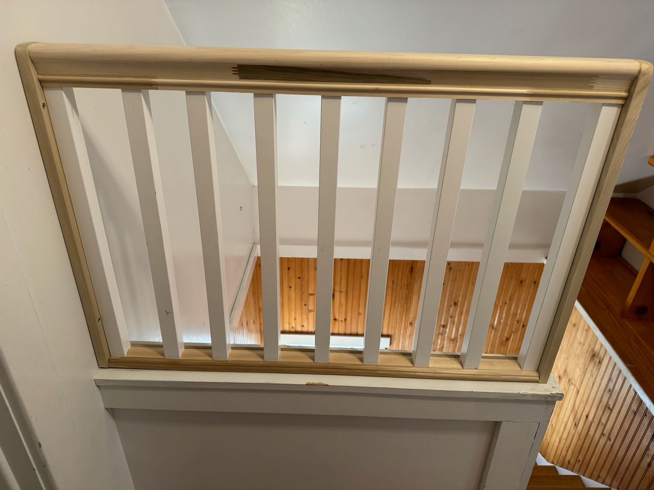 Opposite view of the stair landing railing and wood handrail.