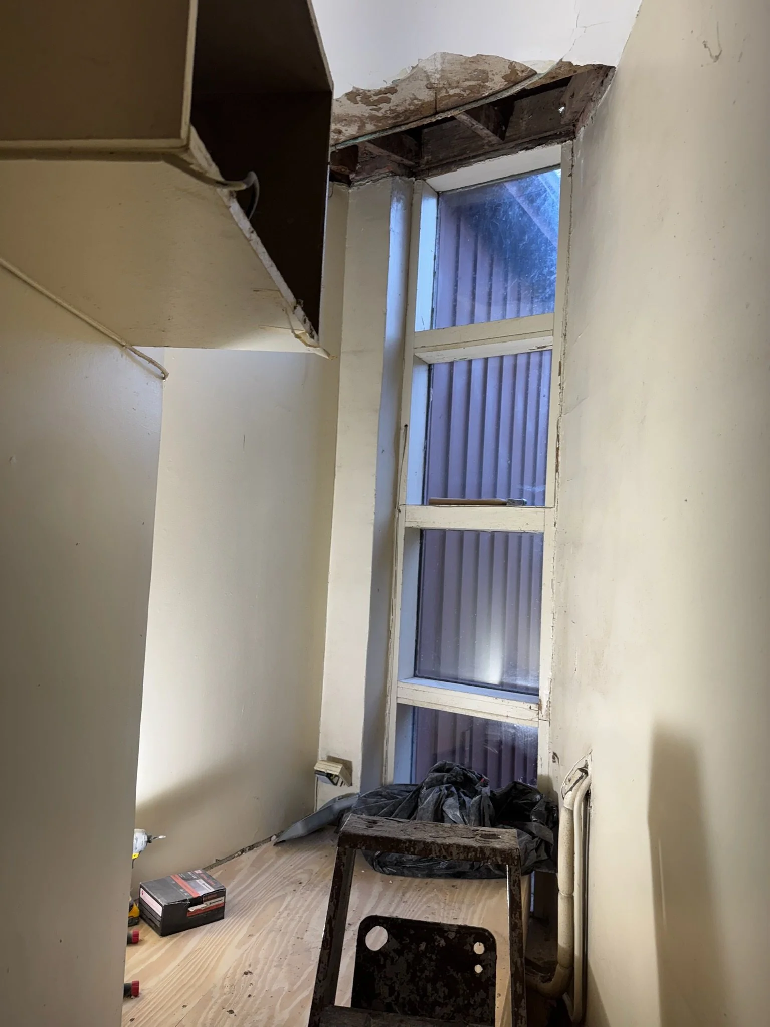 Before repair: damaged ceiling plaster above a tall window.