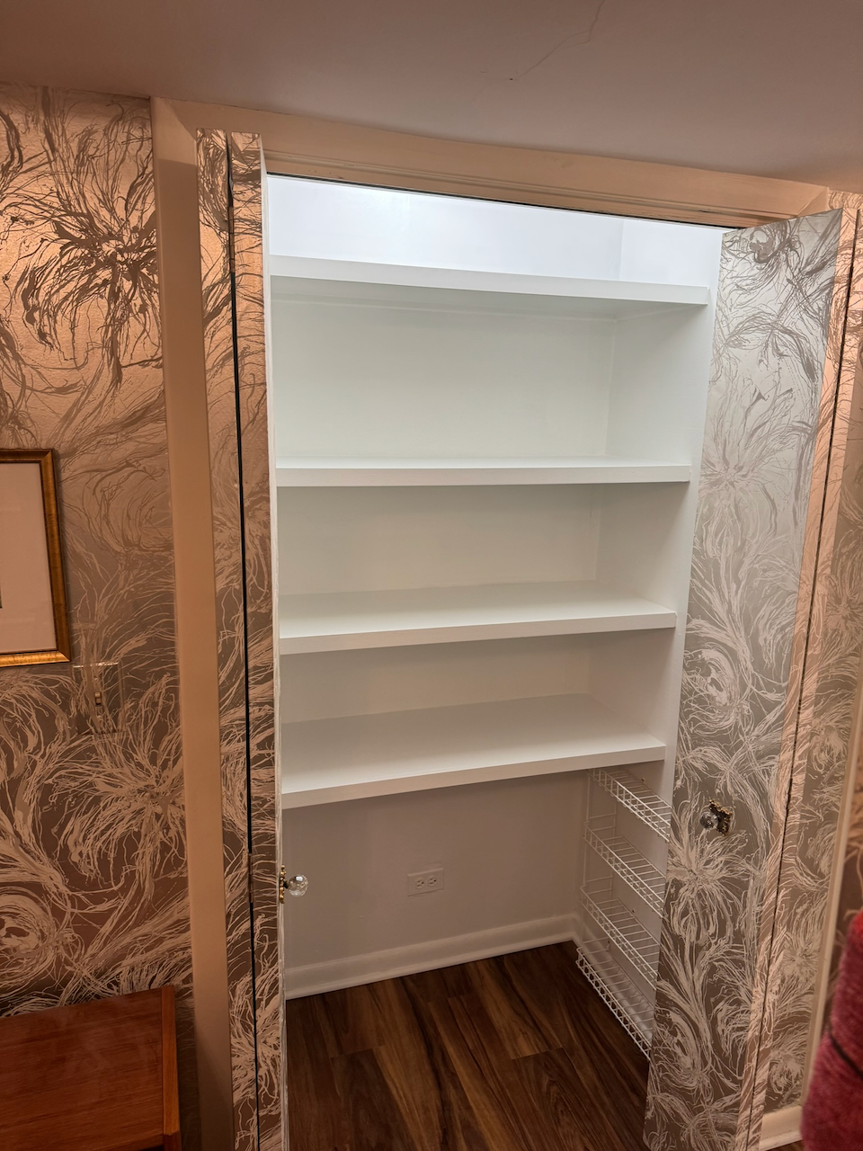 Full view of the recessed shelves through the wallpapered doorway.