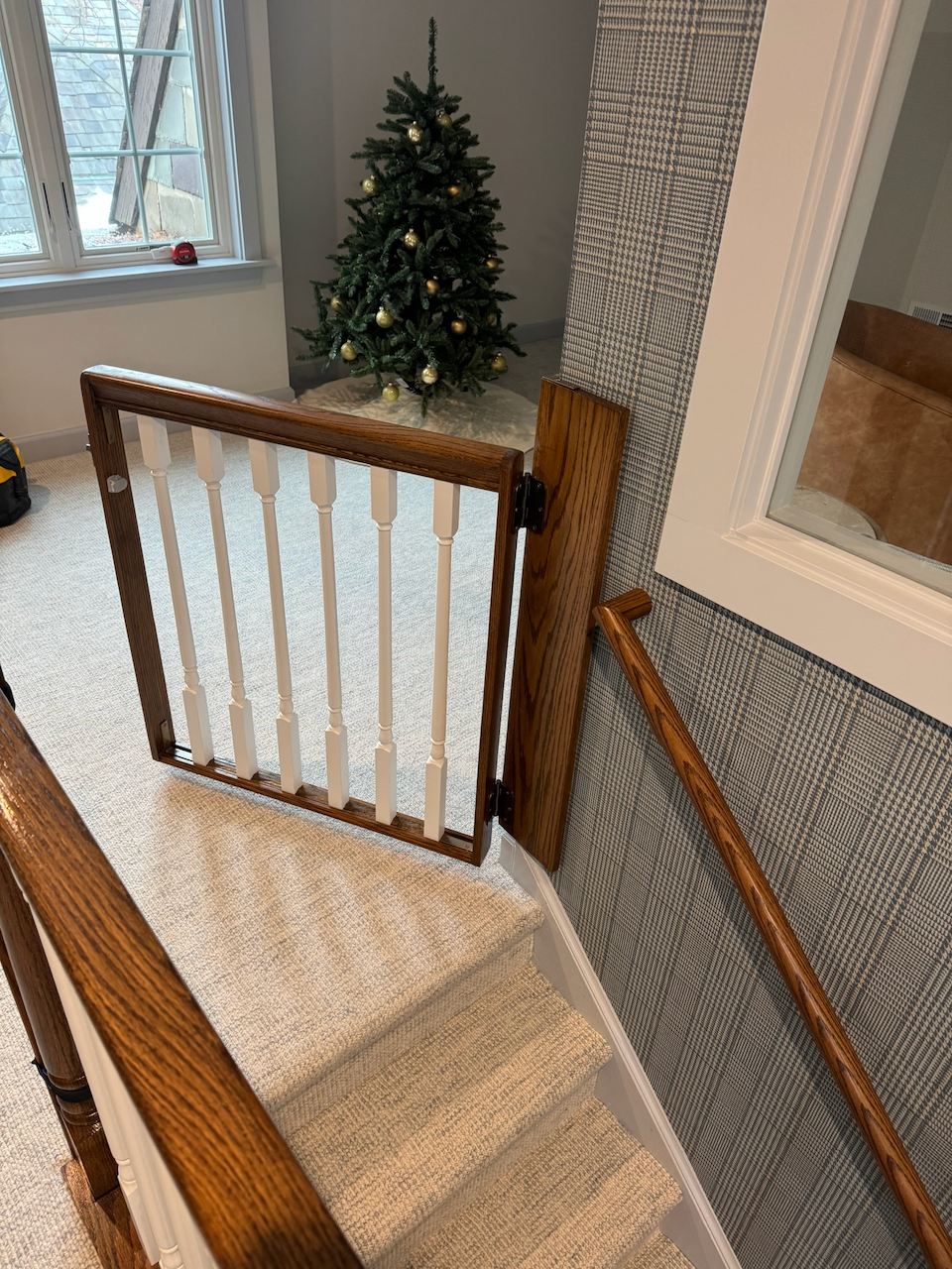 Wood handrail following the stairwell wall beneath the window.
