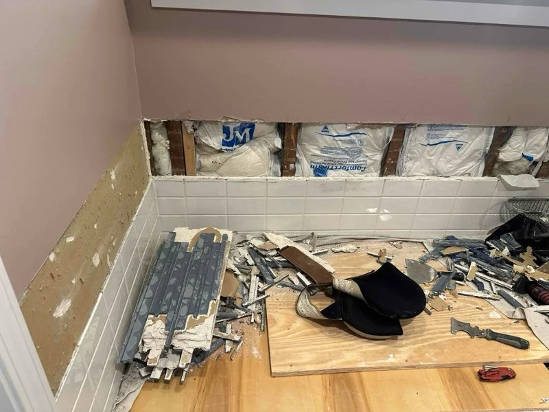 Tile removal in progress, with wall framing exposed before replacement