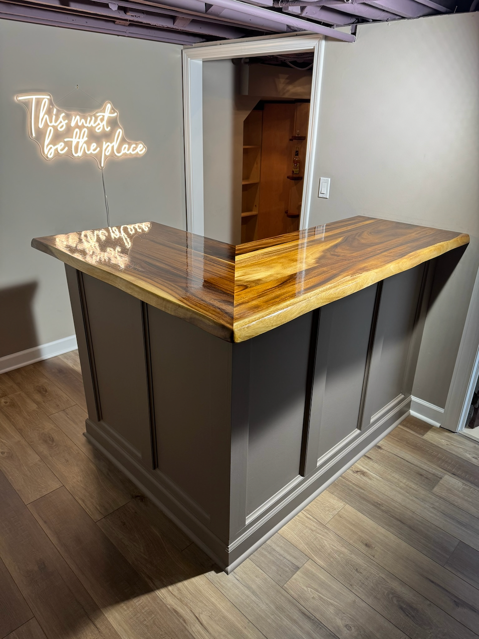 Completed custom bar with dark paneled front and live-edge top.