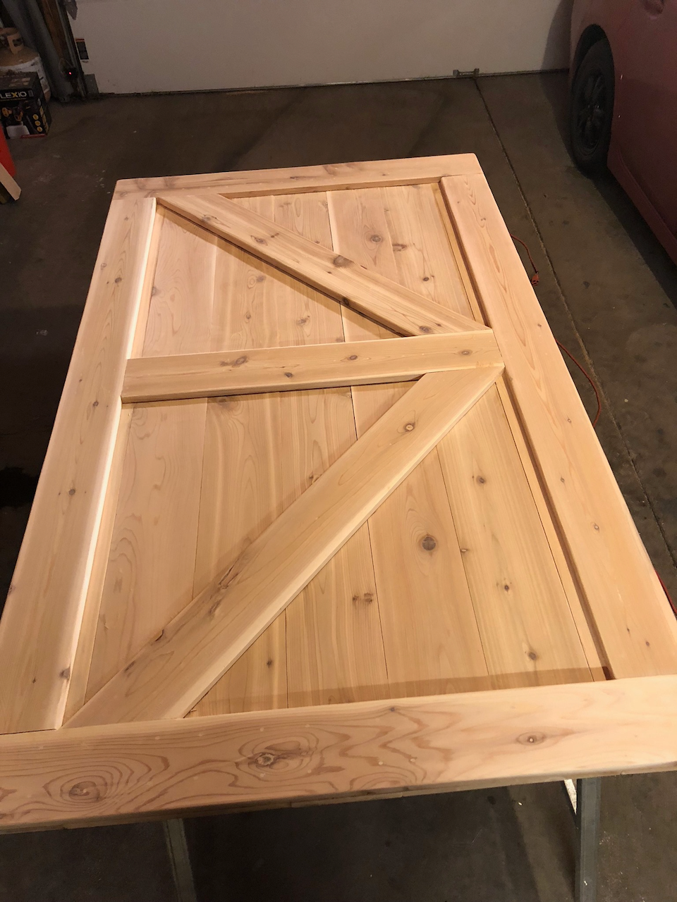 Knotty pine barn door with diagonal bracing during workshop assembly.