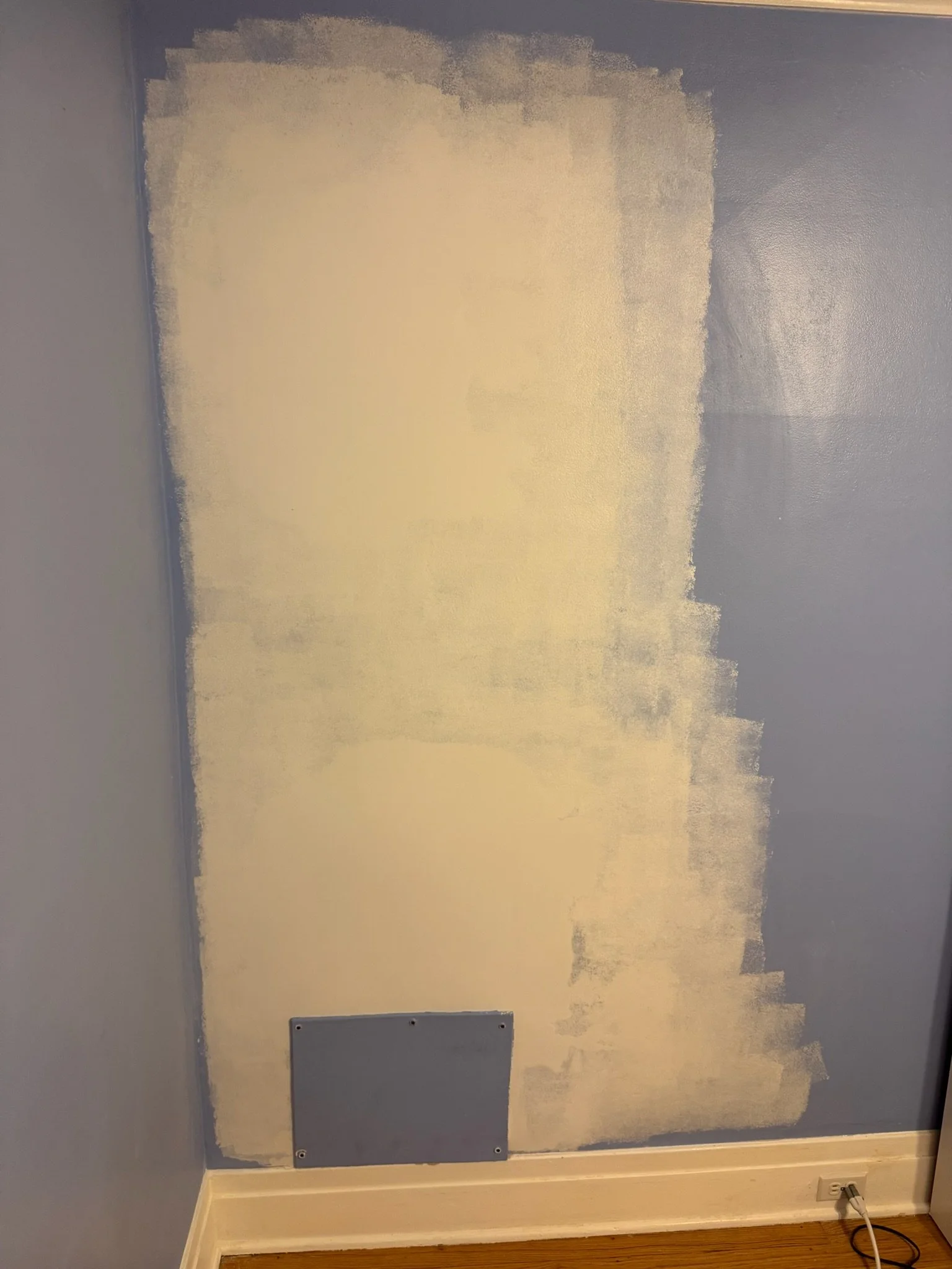 Wall repair in progress: patched surface with an access panel, before painting.