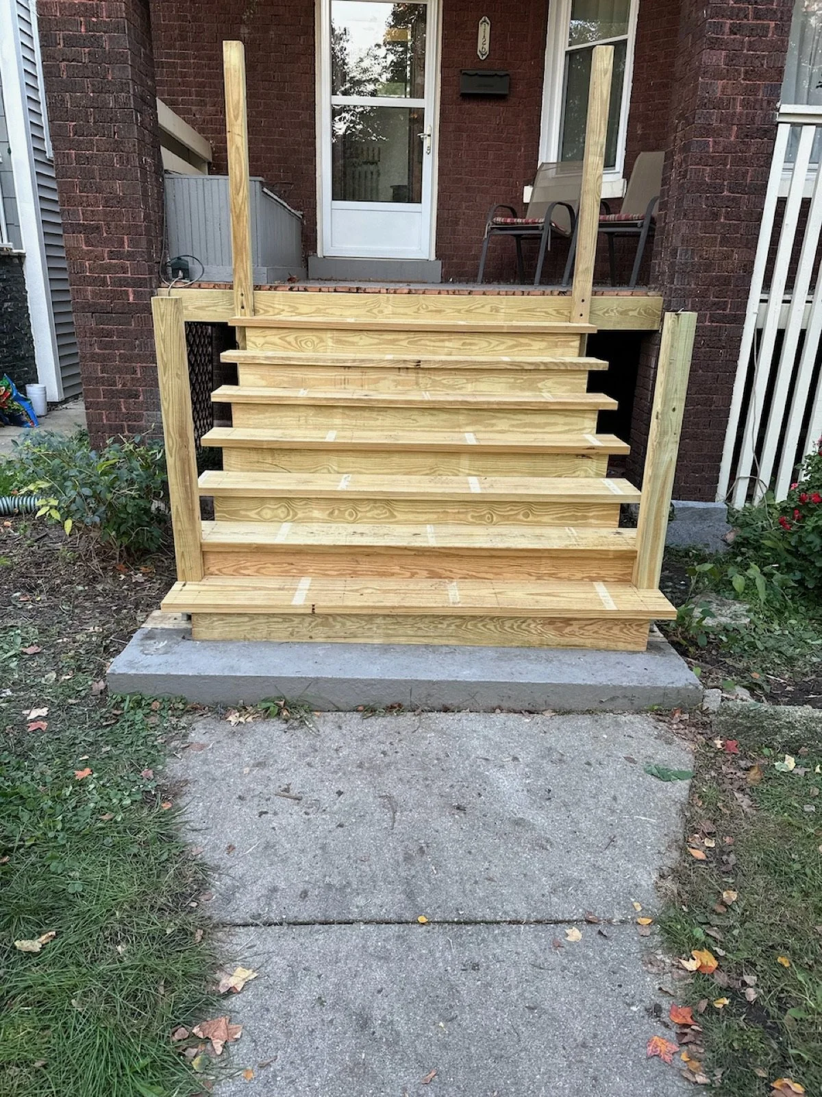 Front porch stairs with newly installed natural wood treads.