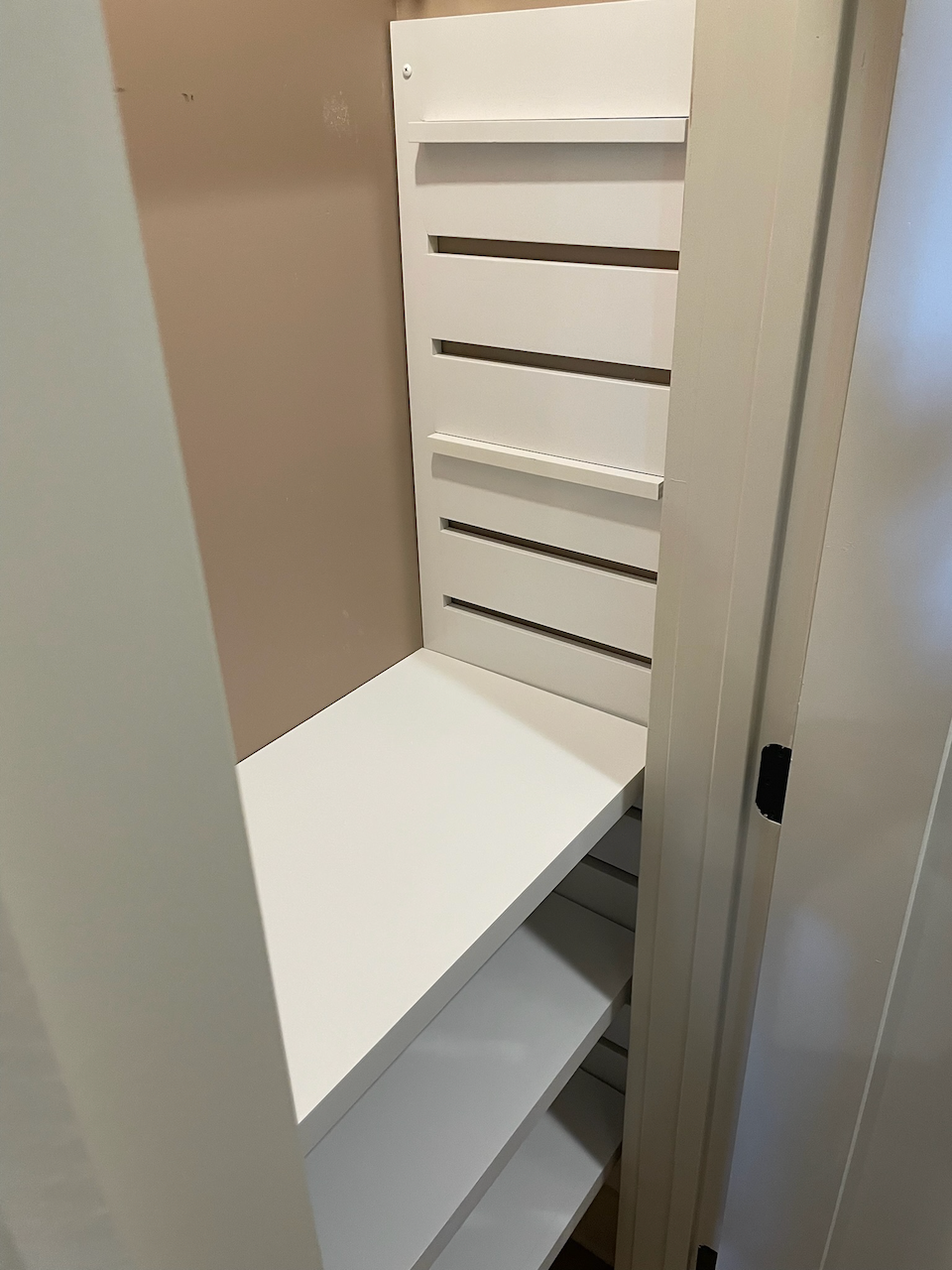 Built-in closet bench with white shoe shelving and slatted side panel.