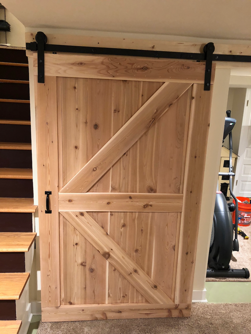 Completed natural pine barn door mounted on black sliding hardware.