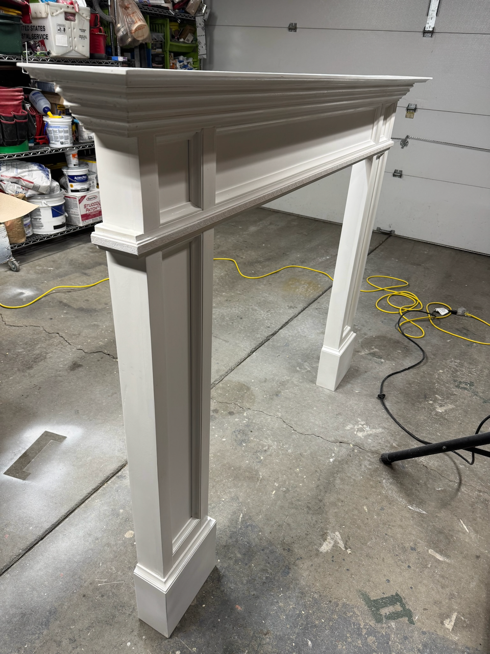 Decorative white fireplace mantel with square pilasters during fabrication.