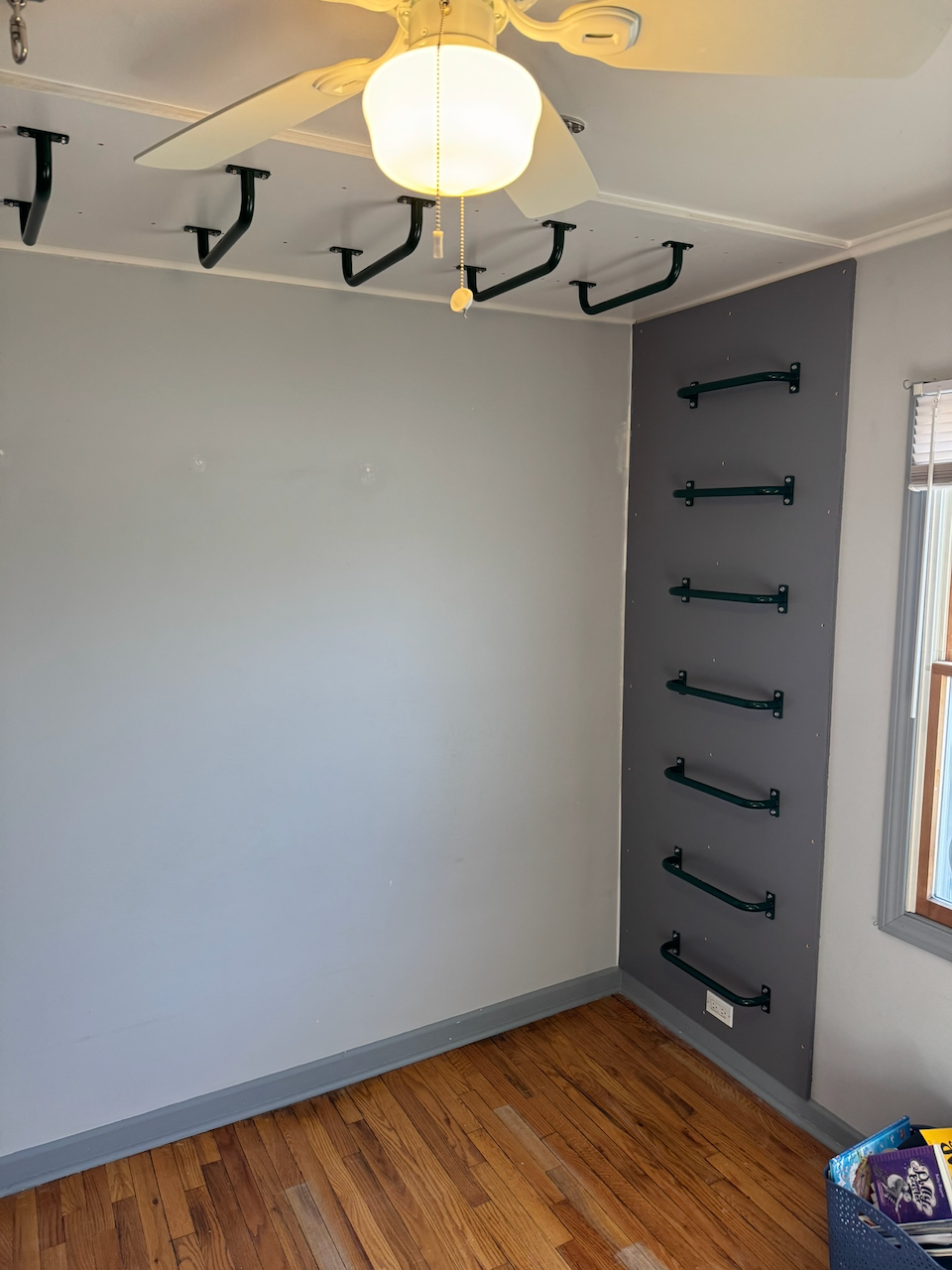 Indoor climbing gym with gray walls and black overhead monkey bars.