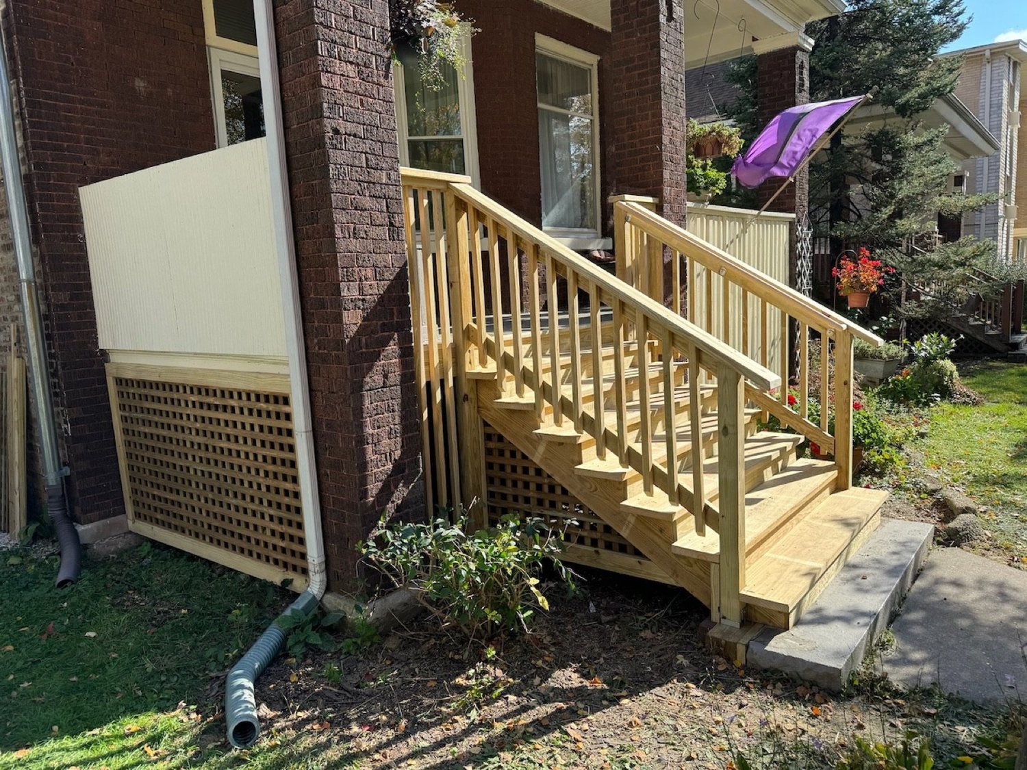 Rebuilt porch stairs with repaired wood lattice skirting.