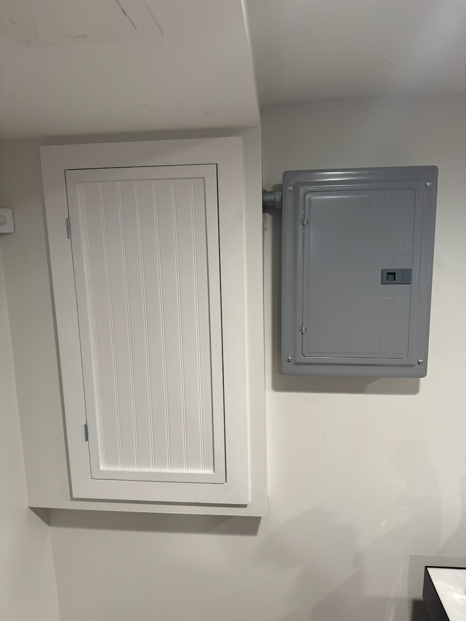 Existing white paneled cabinet beside the exposed utility panel.