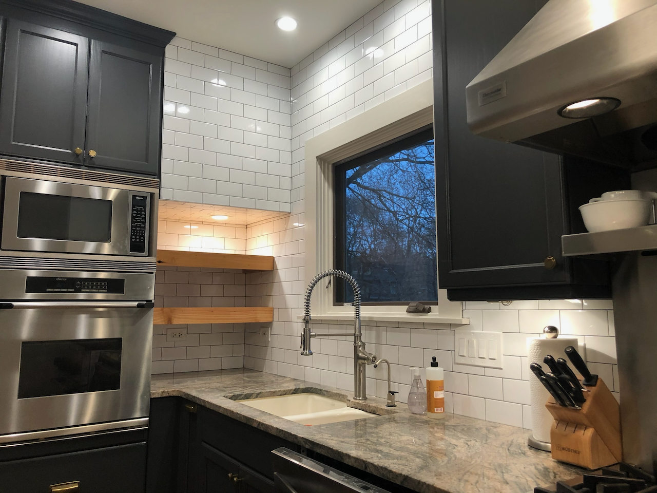 Wider kitchen view showing the illuminated wood shelves.