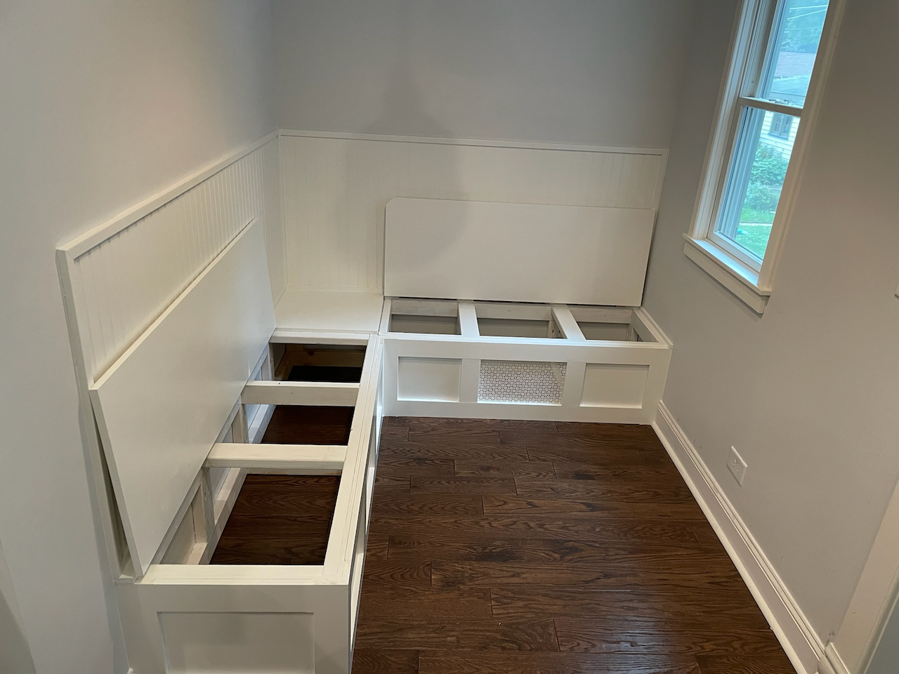 Built-in banquette storage frames fitted around the corner beneath the dining nook window.