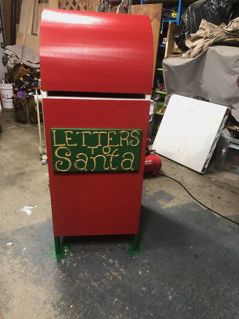 Curved-top Letters to Santa mailbox finished in red and green in the workshop.