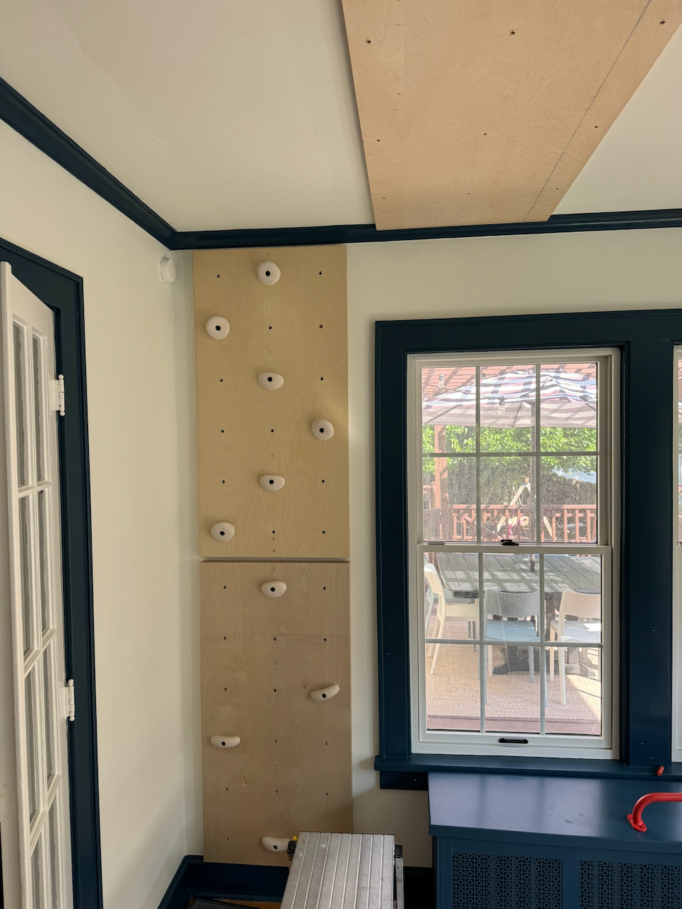 During: wood climbing wall fitted beside the blue-trimmed window.