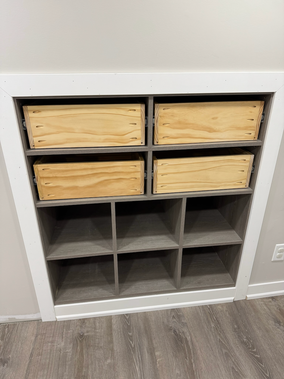 Recessed shoe storage cabinet with wood pull-out trays and lower cubbies.