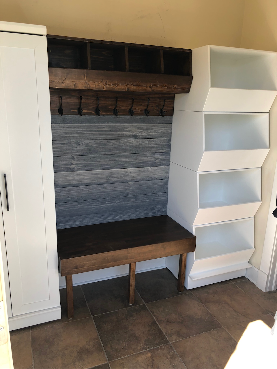 Angled view of the fitted mudroom bench, overhead hook rail and side shelving.