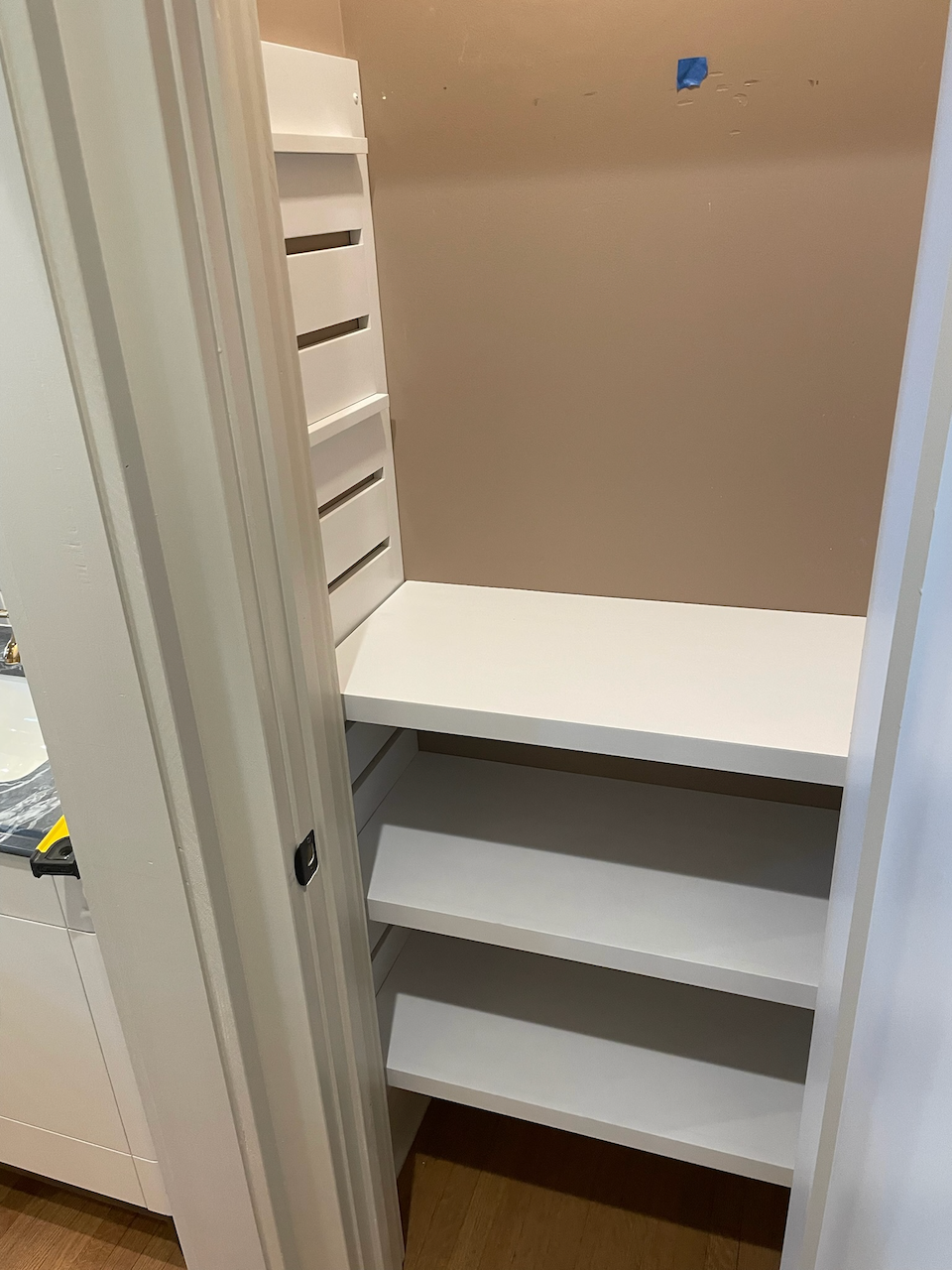 White closet storage bench with shelves below the seat.