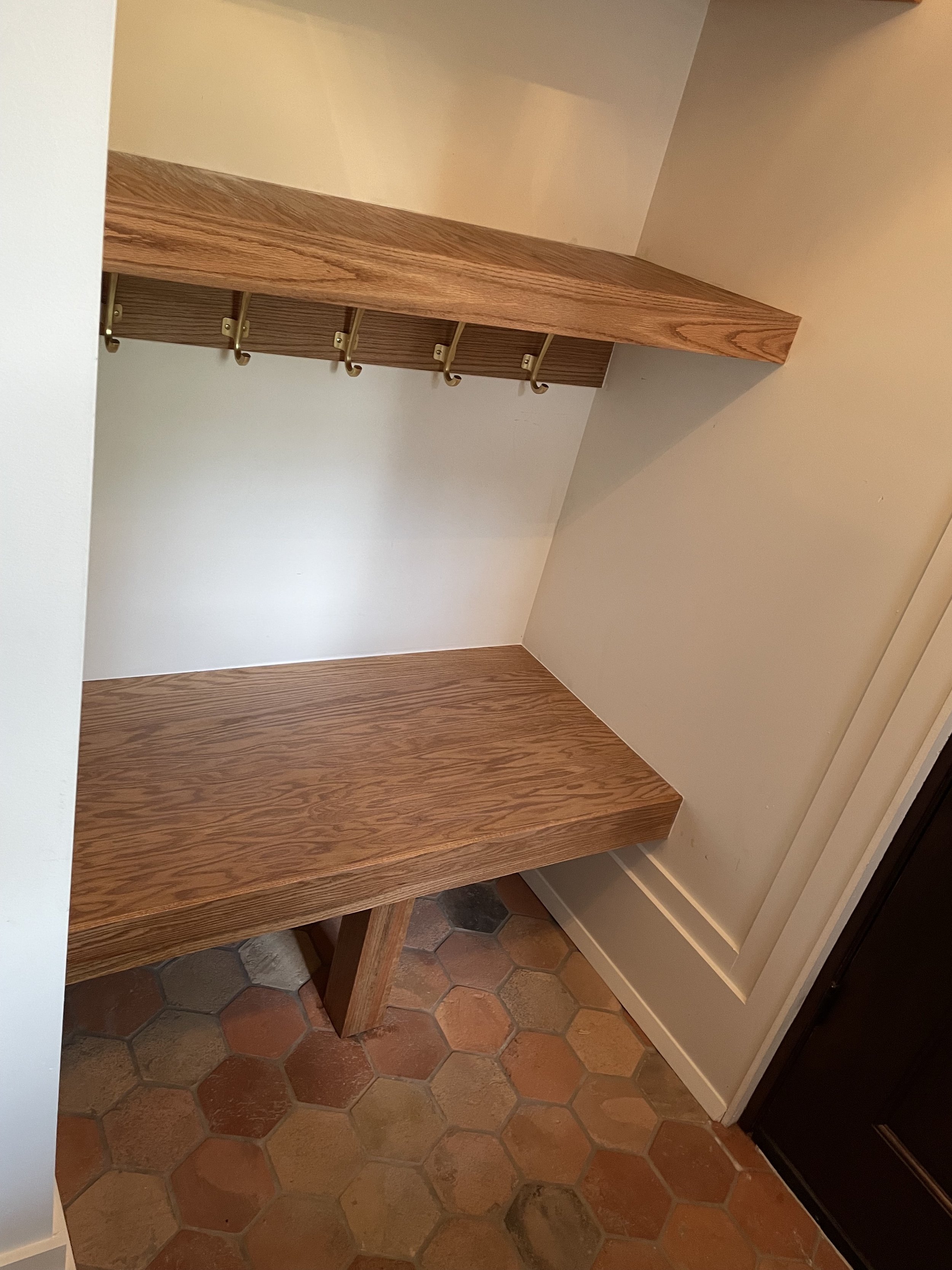 Angled view of the custom oak entry bench and coat hook shelf.
