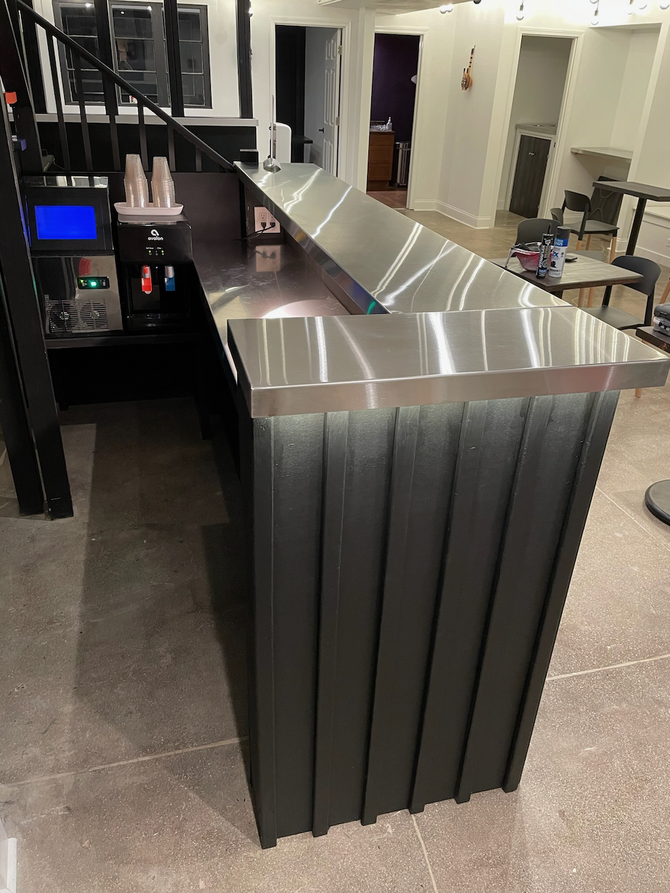 Finished bar corner with dark vertical ribs and metal countertop.