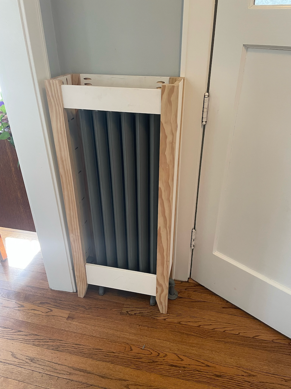 Narrow wood-framed radiator screen with dark vertical slats.