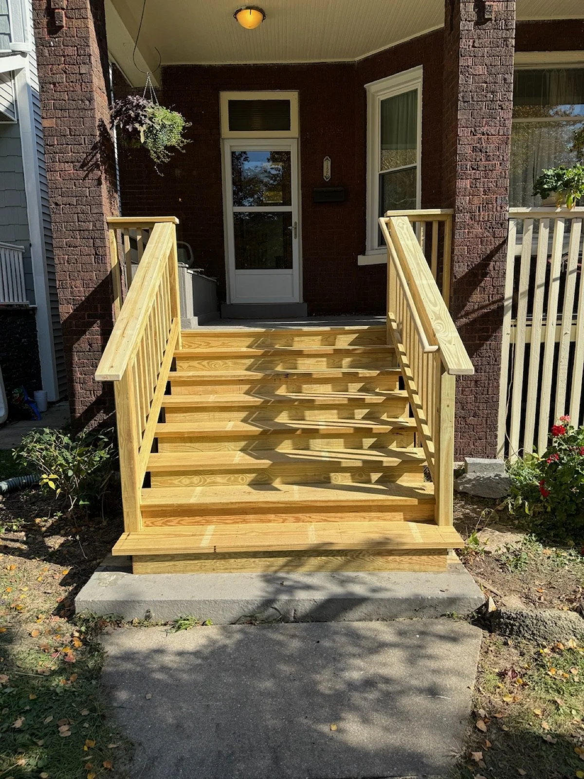 Completed wood porch stair and railing repairs at the front entry.