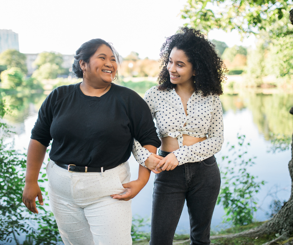 Two women smiling together by a pond, enjoying a secure relationship