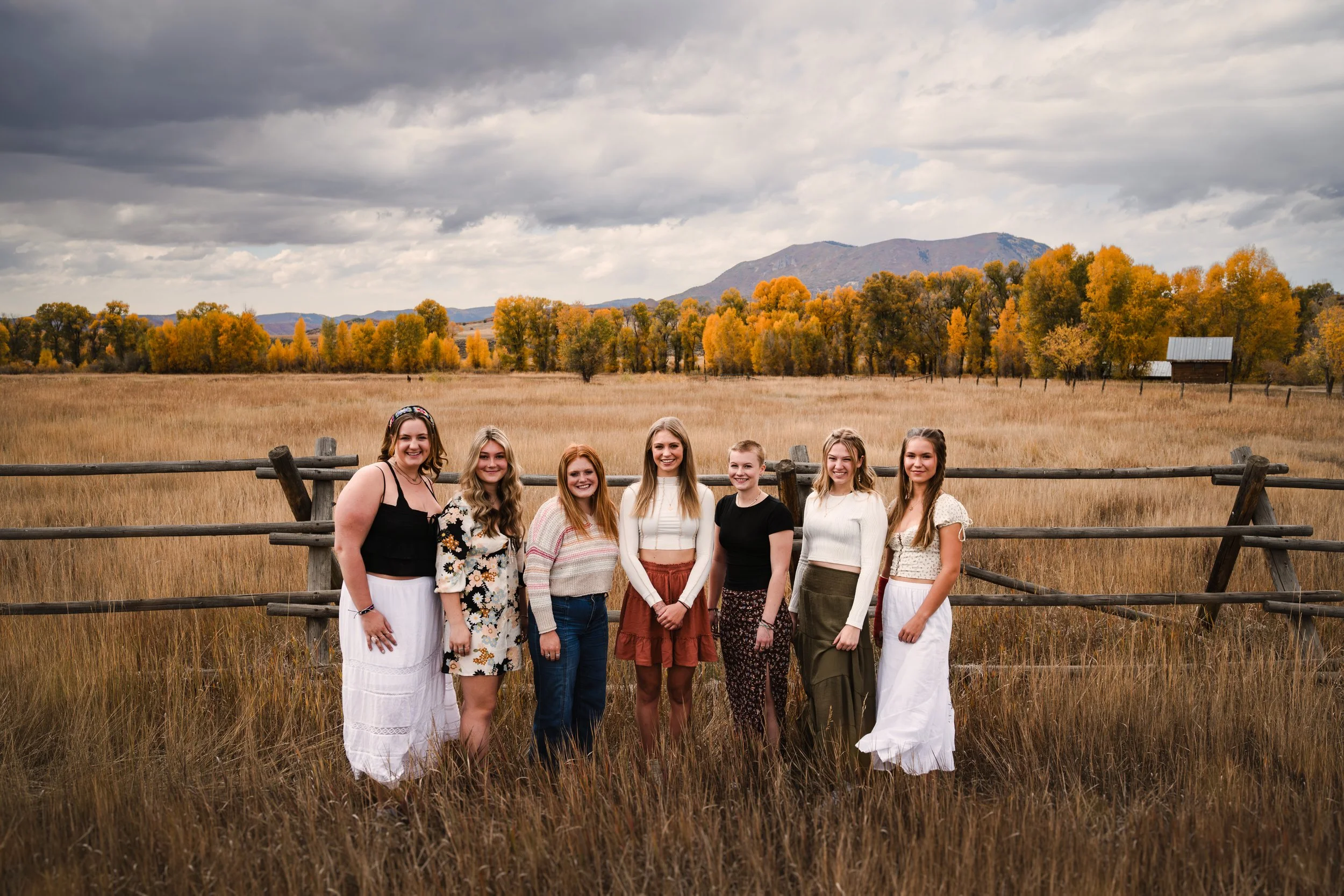 A group of girls in Steamboat Springs in the fall stand together in front of a field and golden aspens for senior pictures by Heather Emerson photography.