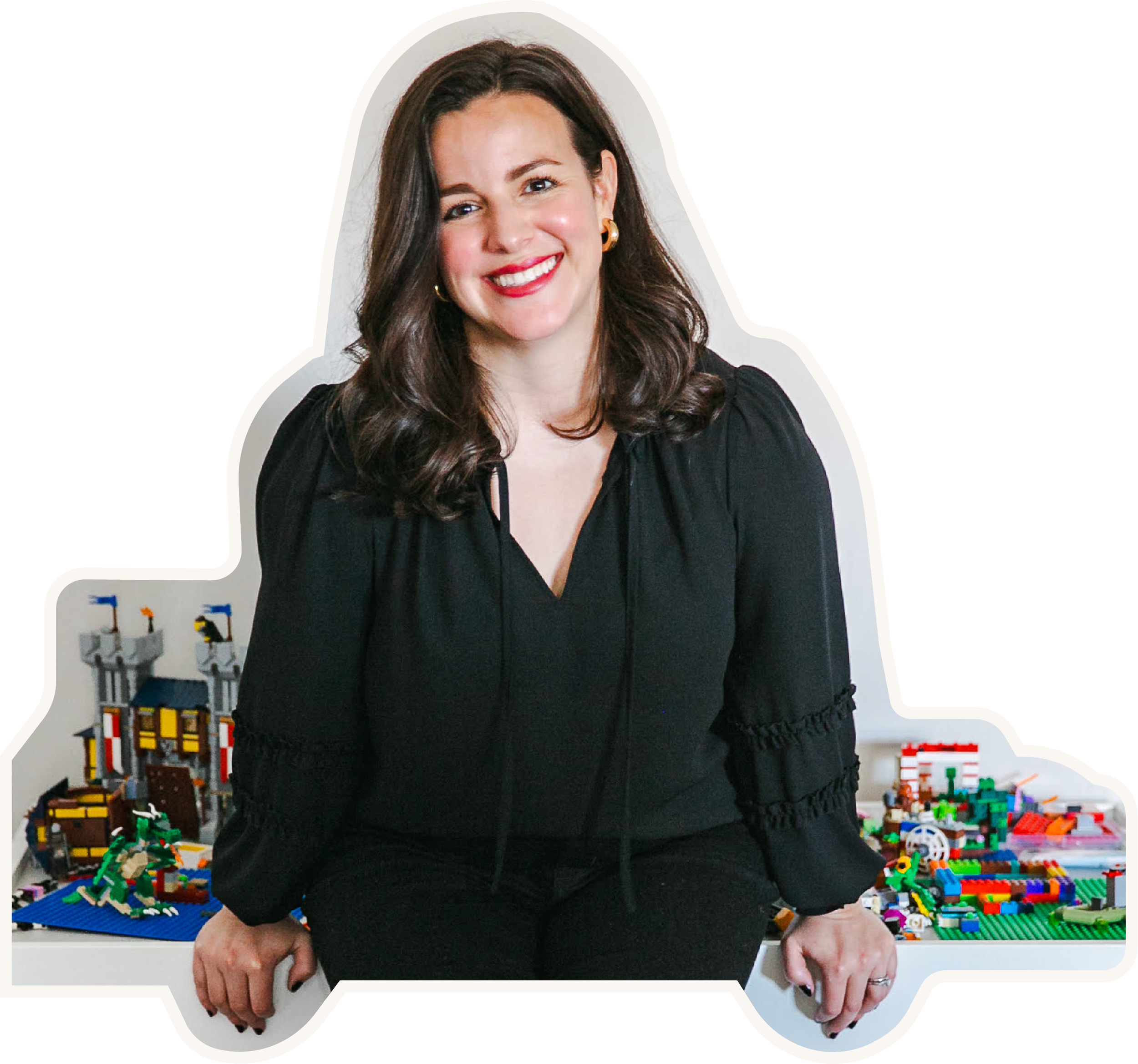 Cut out photo of Katie in a black top and leaning against a table full of lego