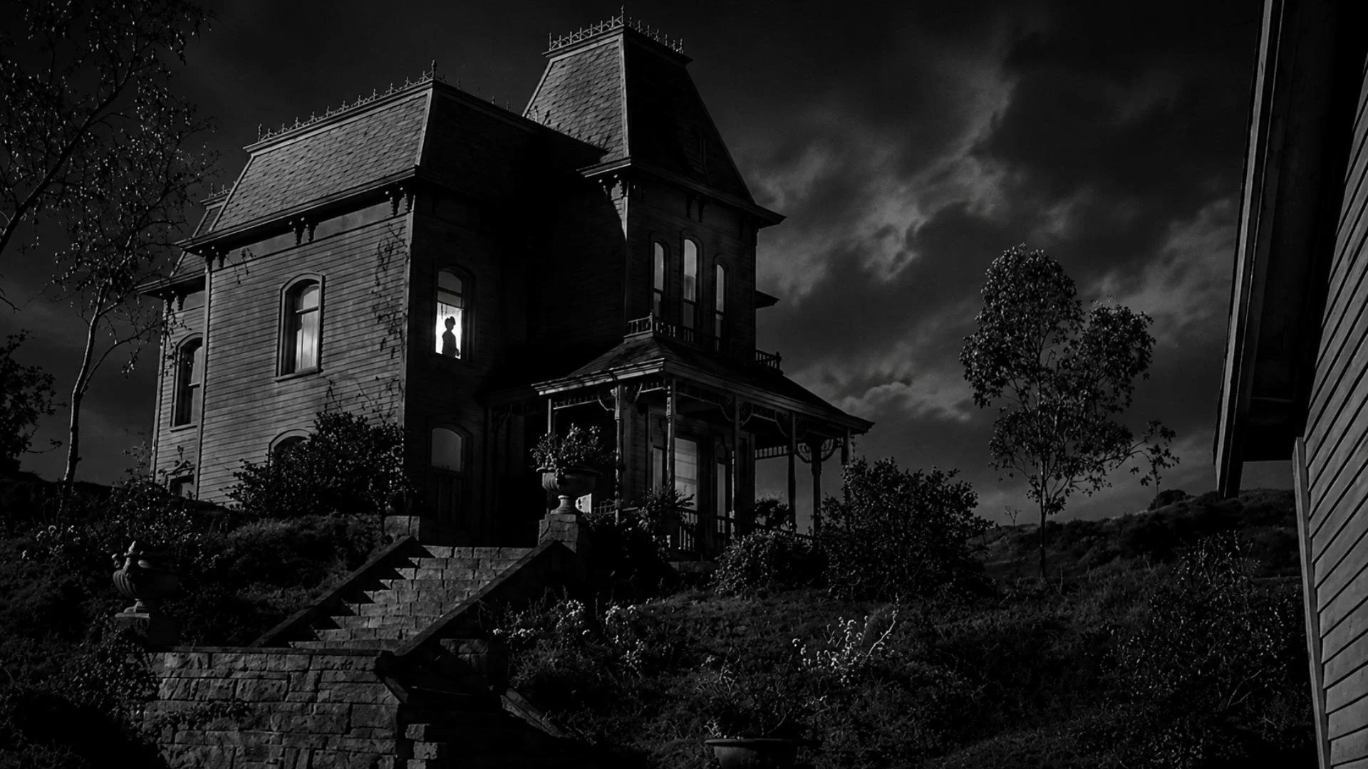 A large gothic house stands on a hill at night