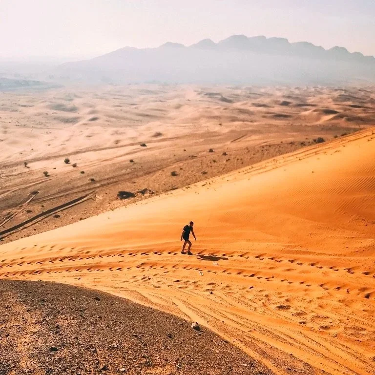 Man walking in sand up a mountain