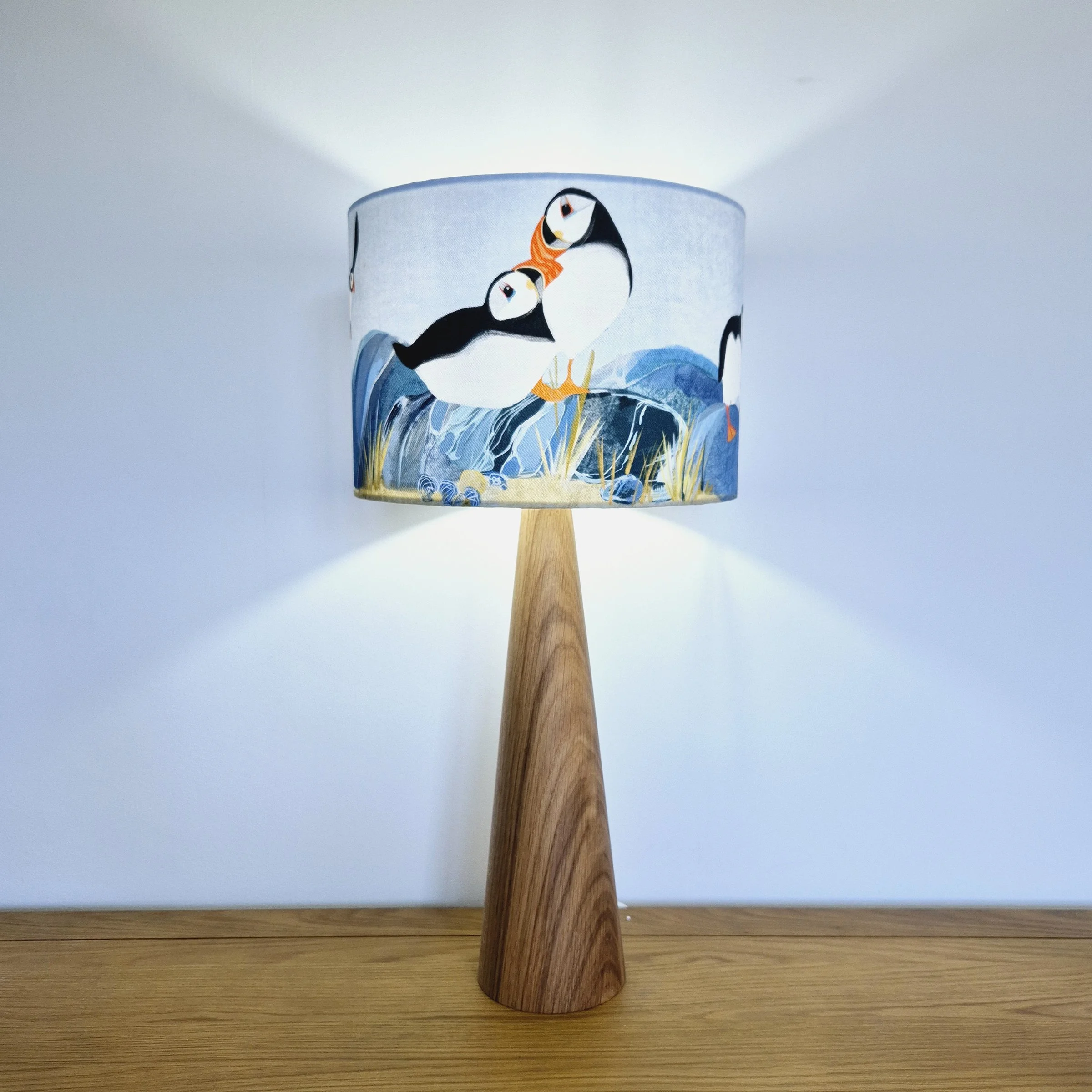 Puffin Island Lampshade by The Hedgerow Artist illuminated on oak lamp base