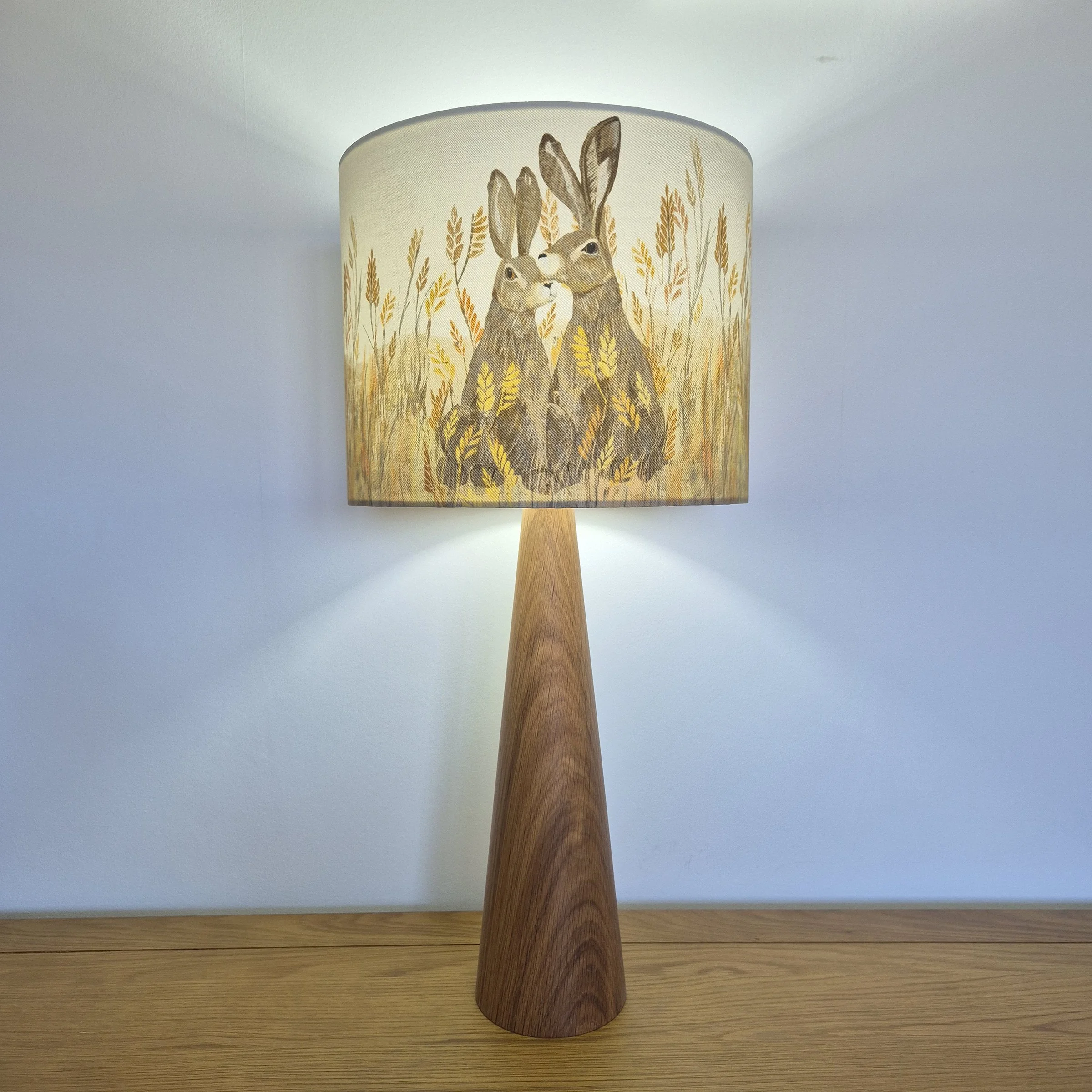 Hares Lampshade by The Hedgerow Artist illuminated on a wooden base