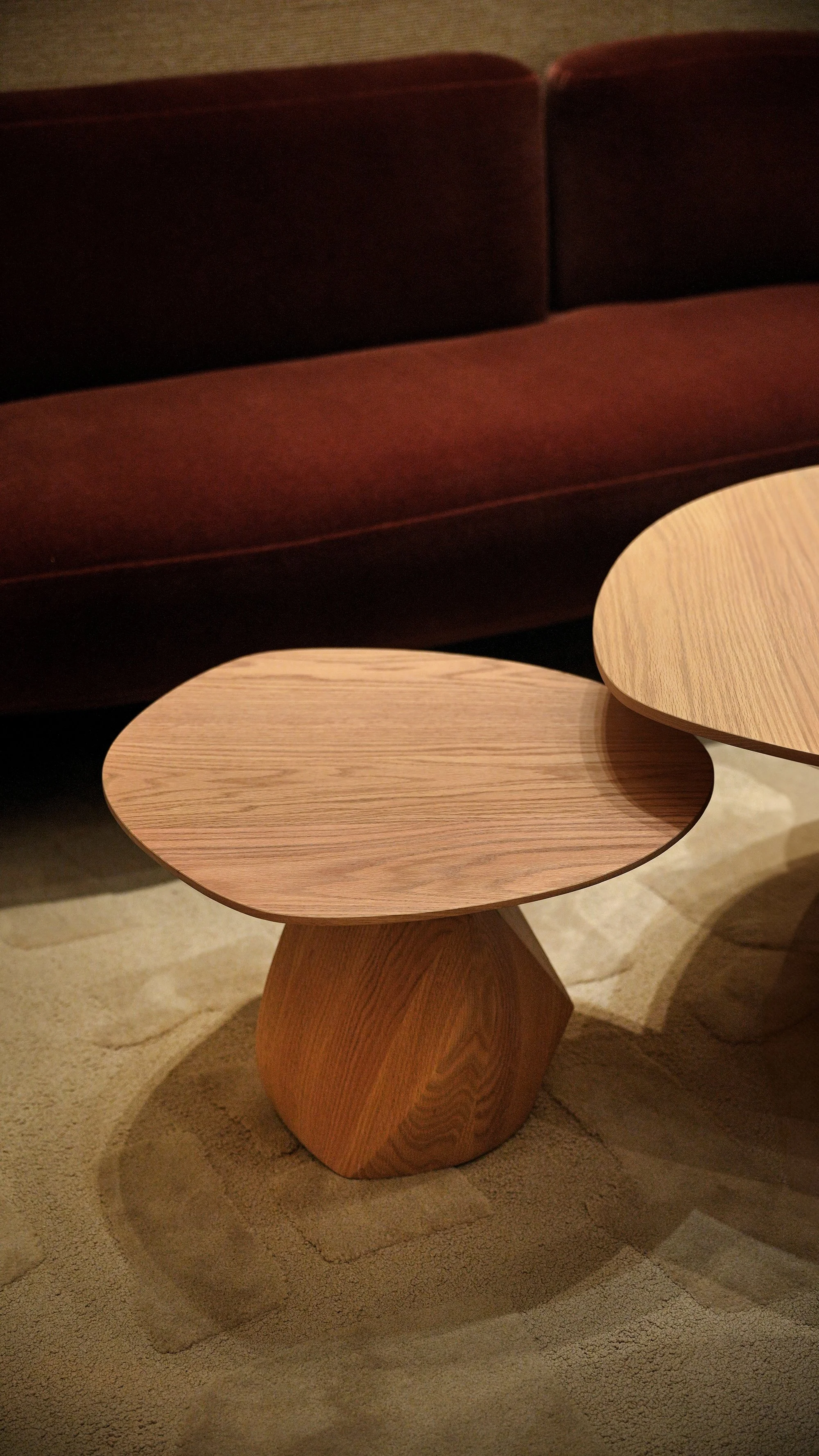 Paired Solace tables forming a coffee table, faceted wood bases with fluid tops.