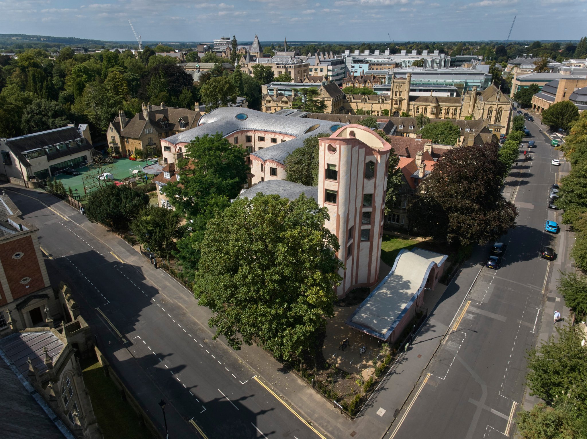 Aerial view of a city with a mix of historic and modern buildings, green trees, and streets with cars.