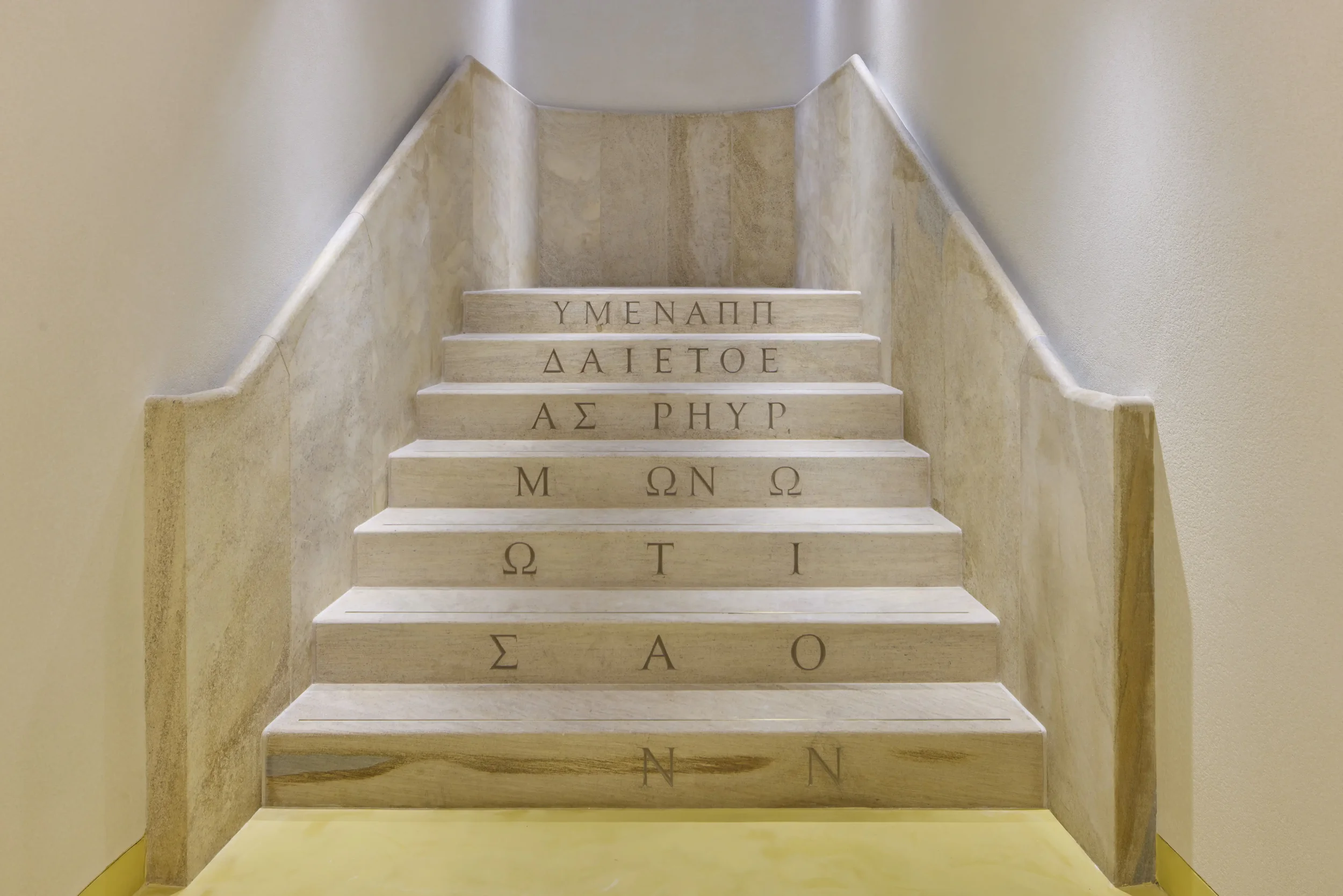 Staircase with carved Greek letters on each step, flanked by plain walls.