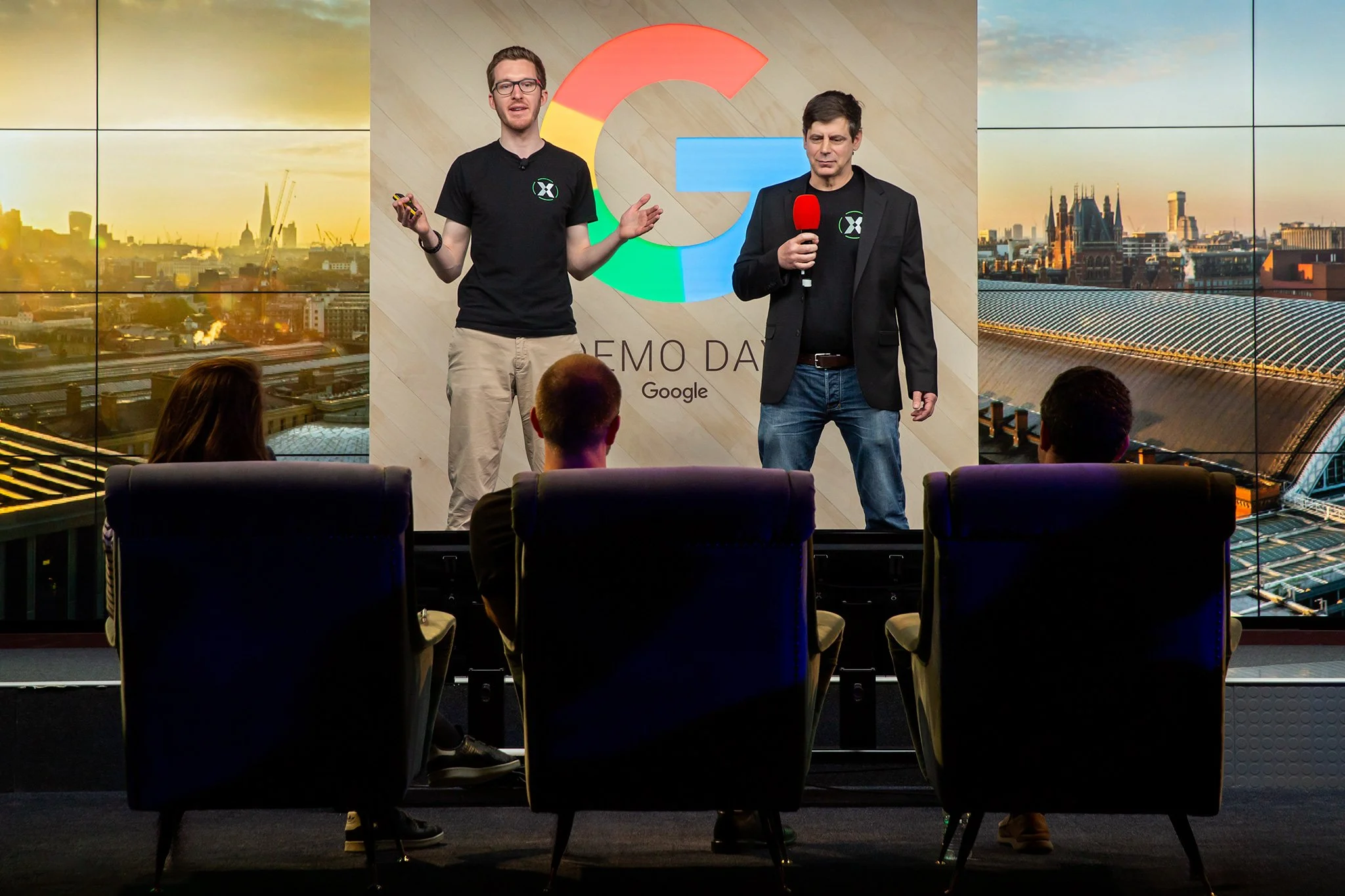 Conference panel session in a dragons den style pitch at Google Demo day in London with two people on stage pitching to 3 industry experts