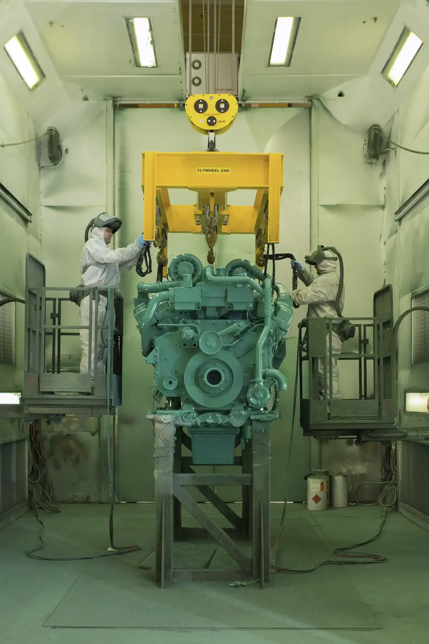 Workers in protective suits operating machinery inside a clean laboratory environment.