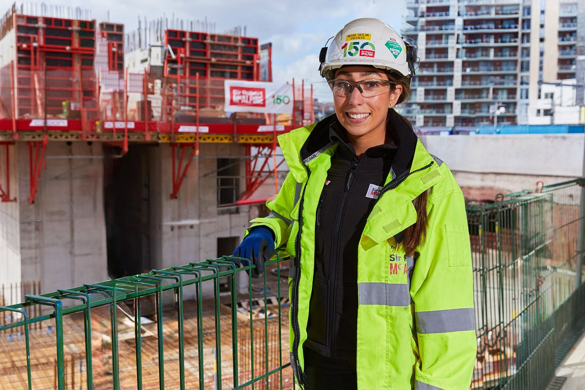 Corporate Photography a smiling woman in a yellow high-visibility jacket and protective helmet standing on a construction site poses for a portrait