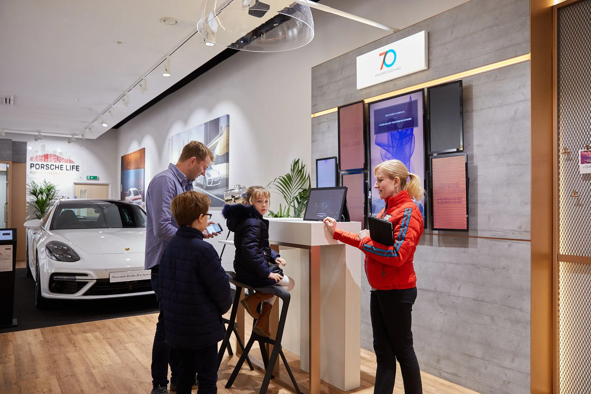 Porsche Store Corporate Photography with family being given a demo of a sound and light experience live in store