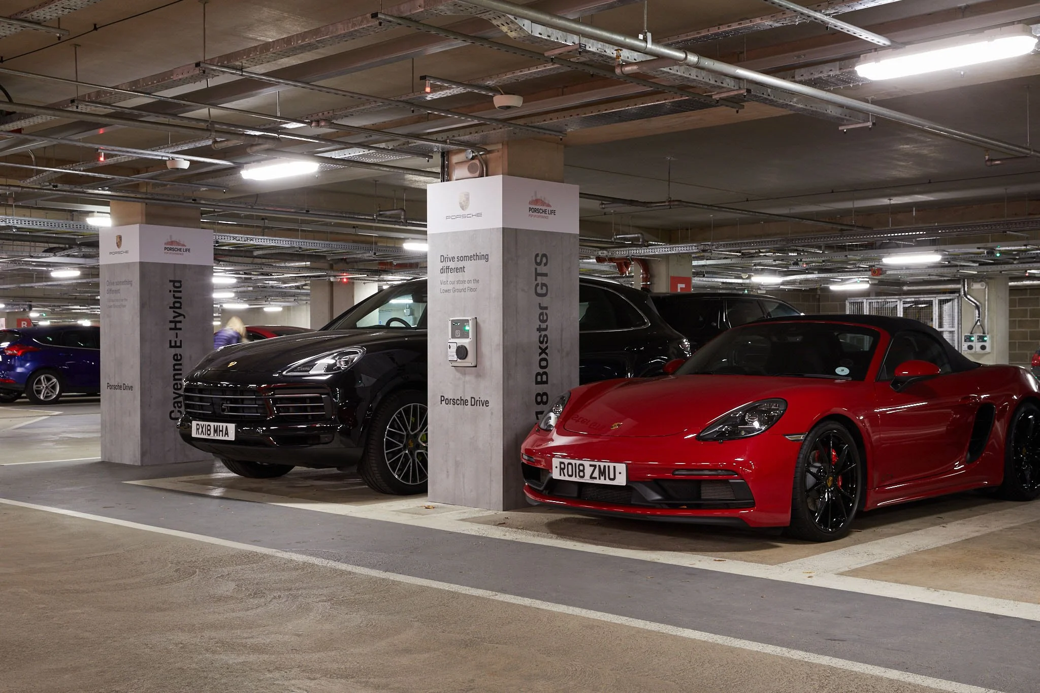 Porsche driving experience from the car park of a shopping centre with a red 911 and black macon ready to drive