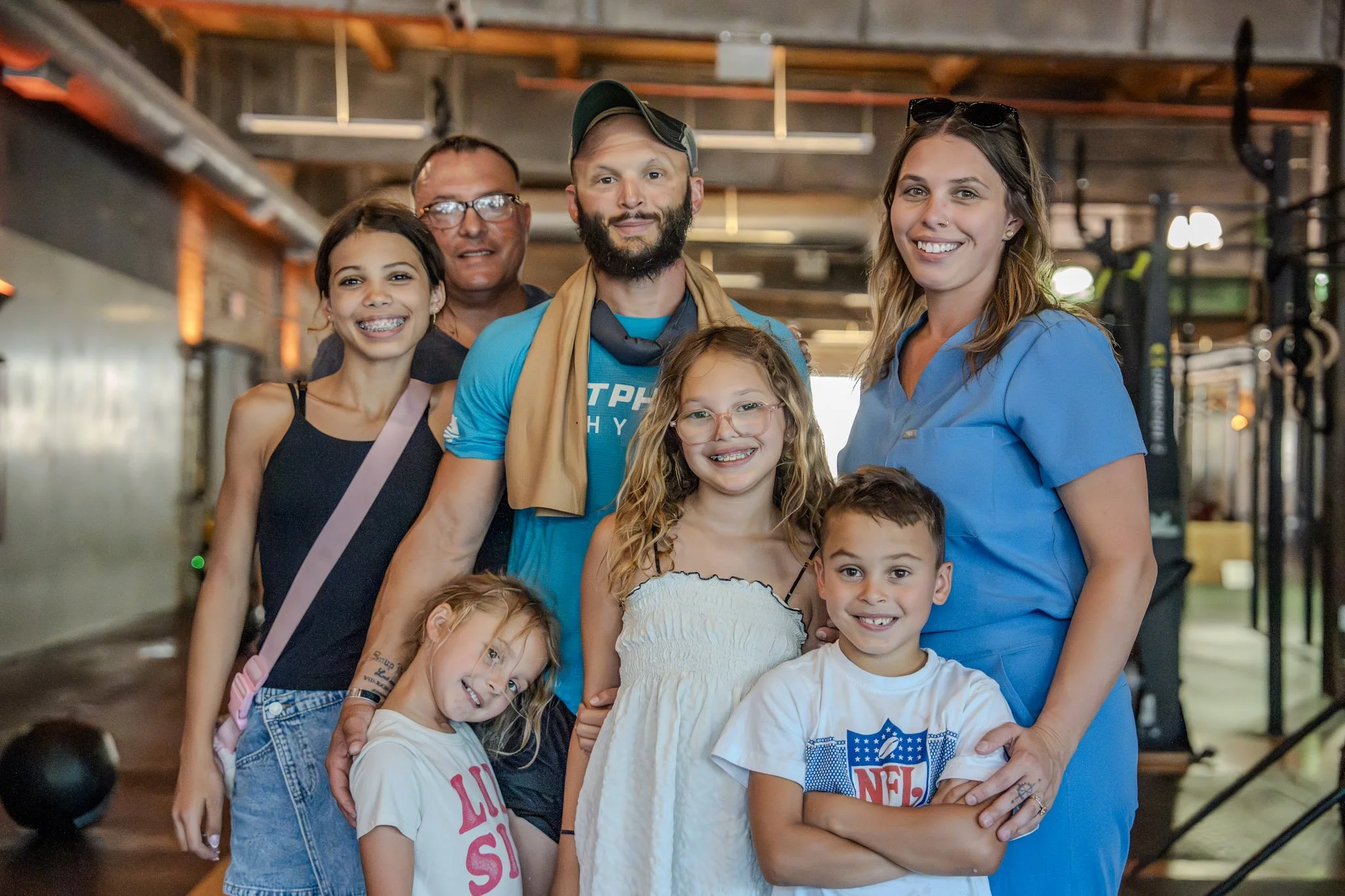 Group of kids and adults smiling in a gym or fitness center