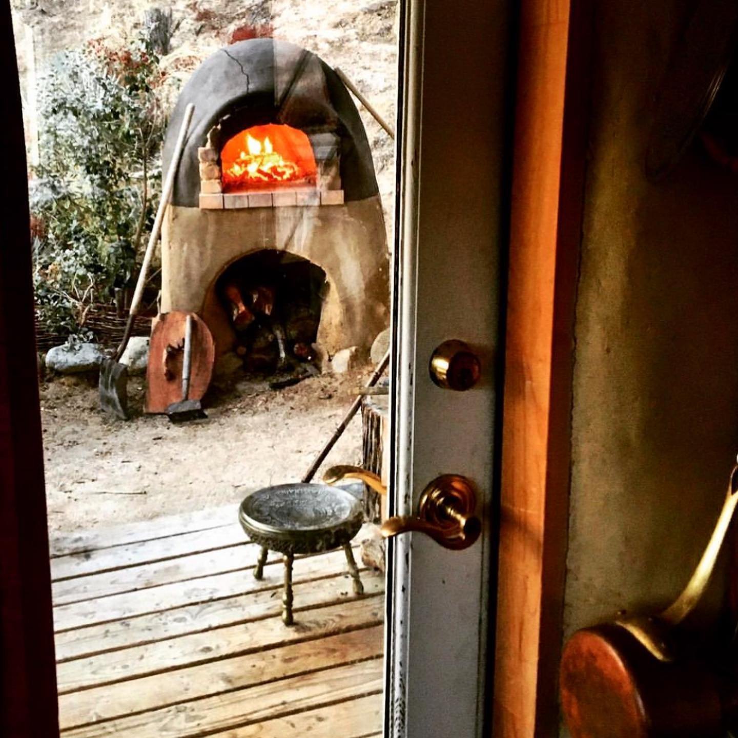 Location is a critical part of any cob oven design. We want space for friends to gather nearby, but I also want to be able to see inside the oven from the kitchen. This way I can keep an eye on the fire while prepping food inside the kitchen. A sligh